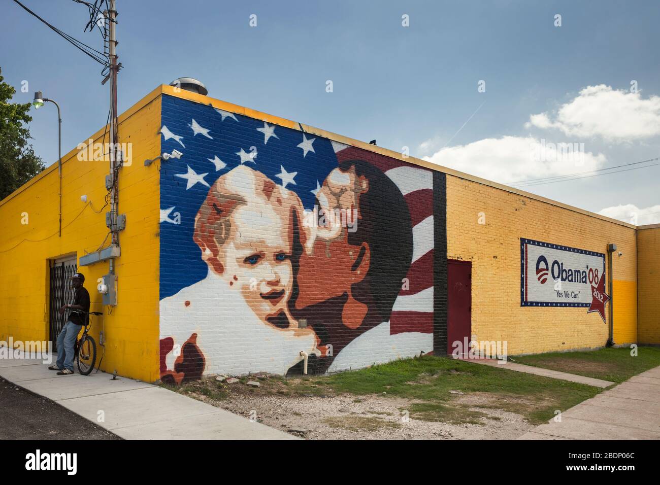 obamas-mural-of-electoral-propaganda-on-a-yellow-wall-close-to-a-black-race-man-leaning-on-a-bicycle-west-alabama-st-midtown-houston-texas-2BDP06C.jpg