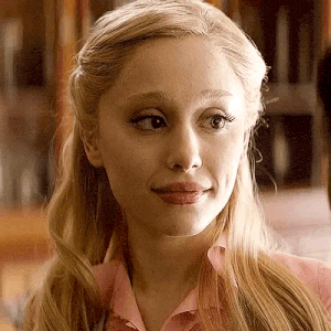 a close up of a woman 's face wearing a pink shirt and looking at the camera .